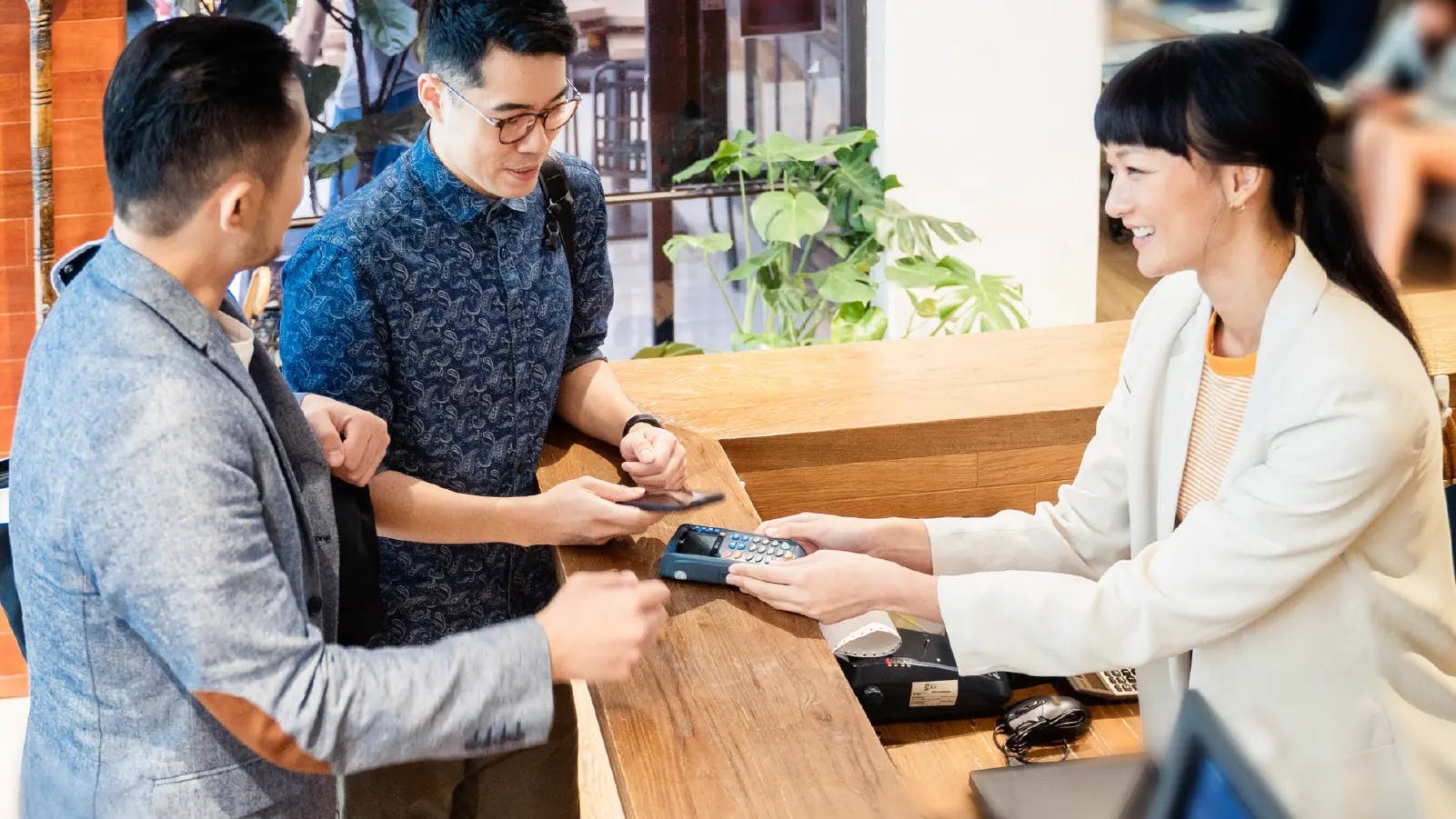 contactless payments_group of people checking nto hotel using contactless payment device